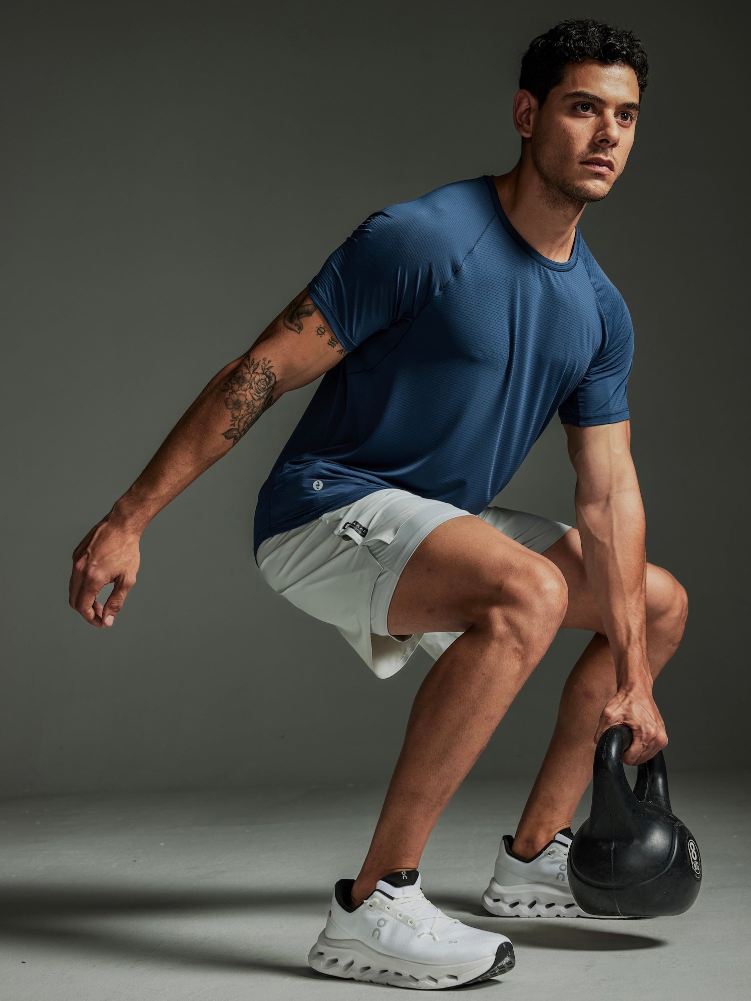 Man in TECHTEE athletic wear holding a kettlebell against a gray background