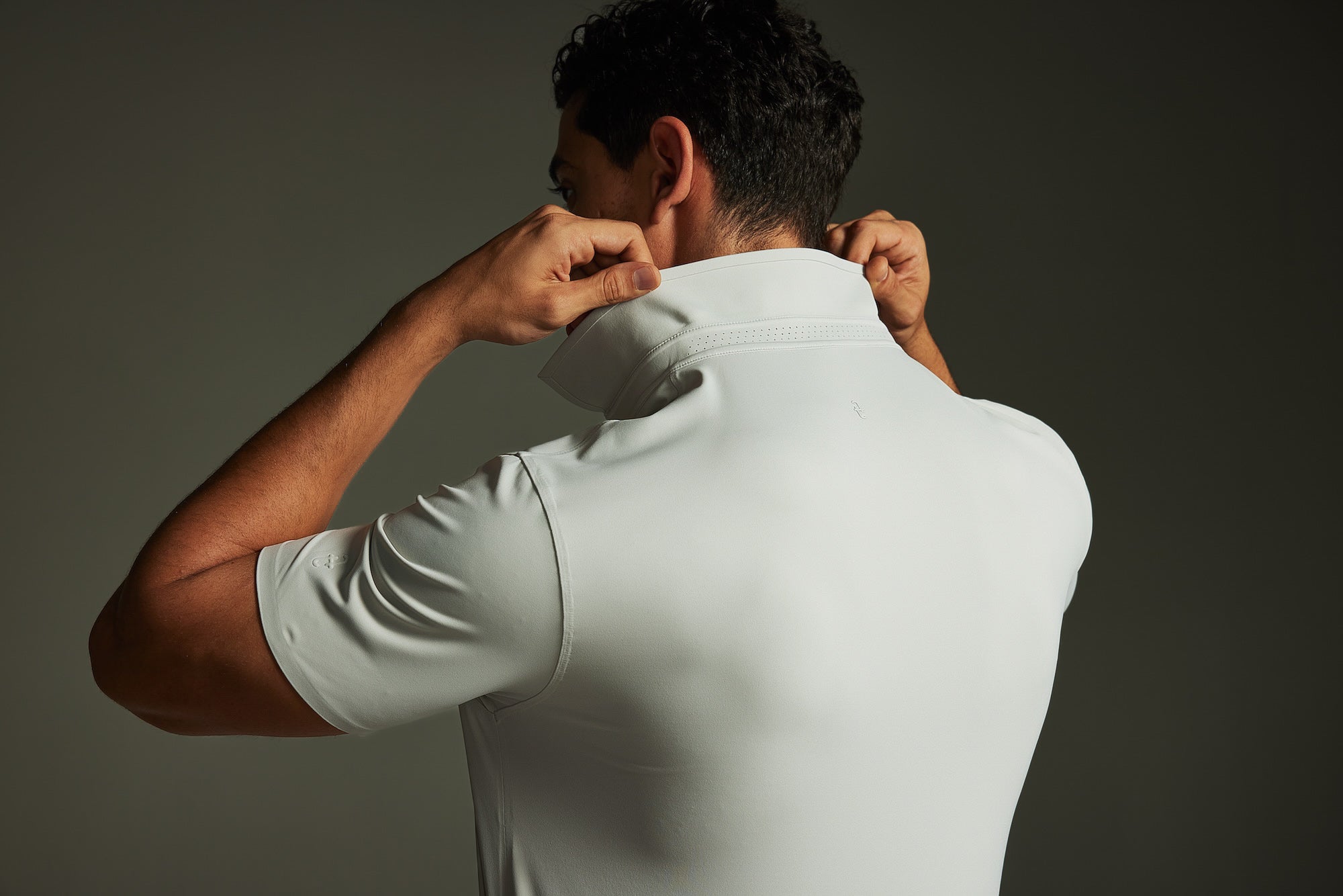 Person wearing a TECHTEE grey polo shirt against a dark background