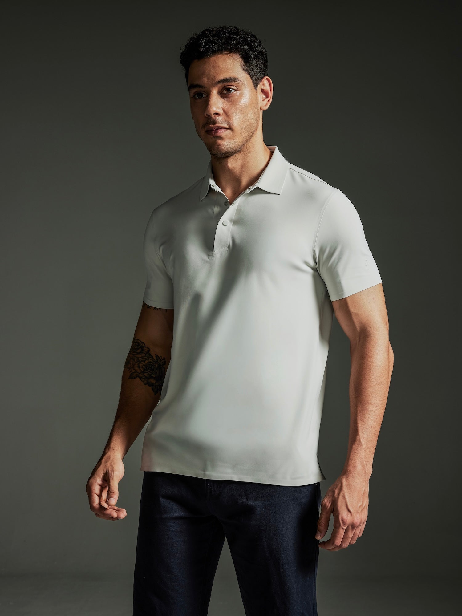 Man wearing the TECHTEE light gray polo shirt against a dark background
